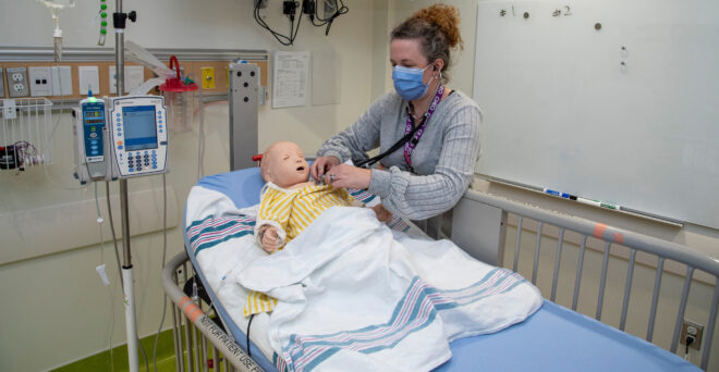 A nurse training with a Sim Doll.