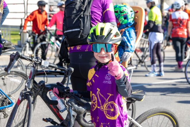 Child cyclist smiling, giving thumbs-up at CN cycle event.